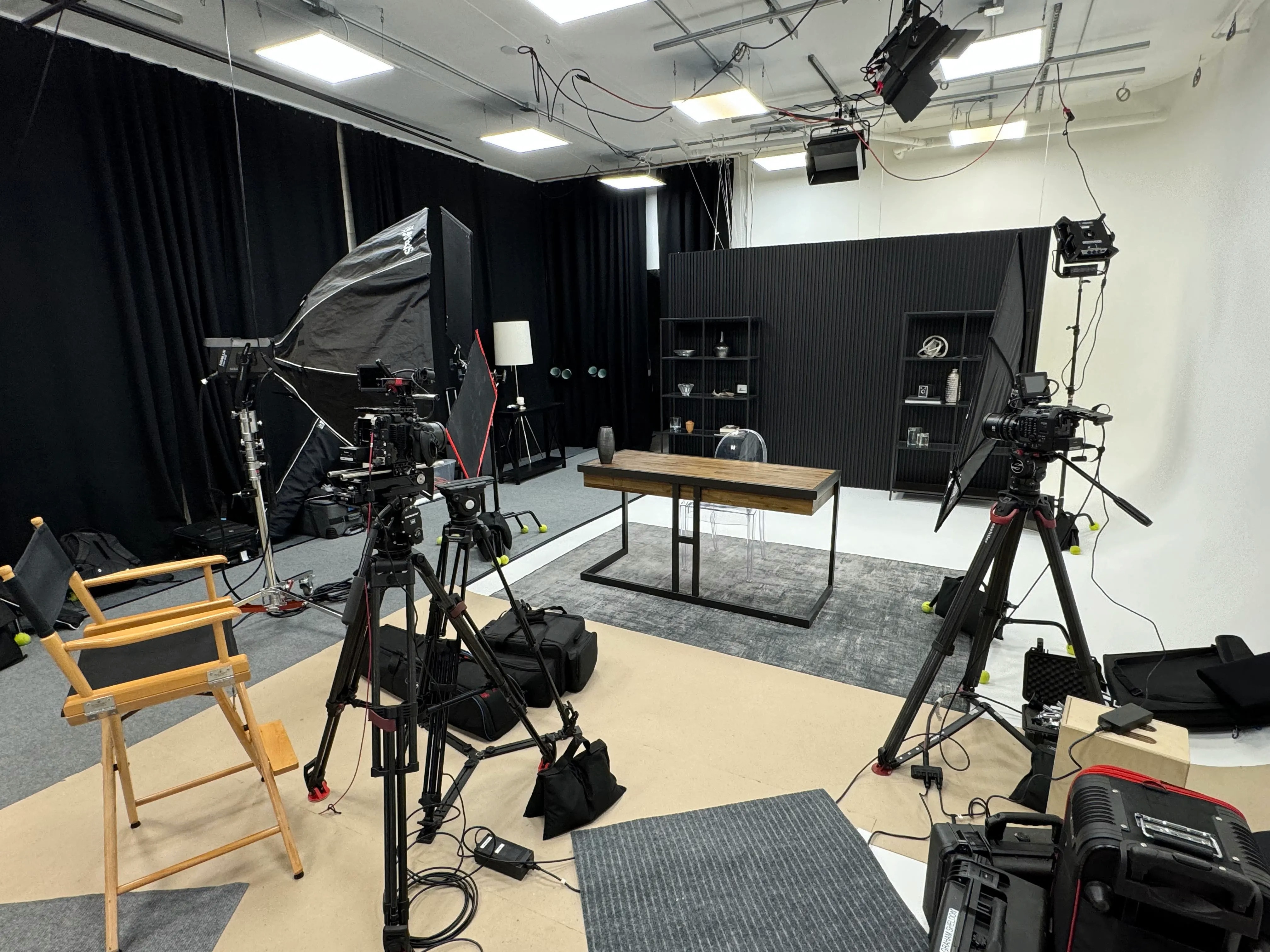 Interior of REV Studios set with cameras, lighting, a desk set, and black curtains.